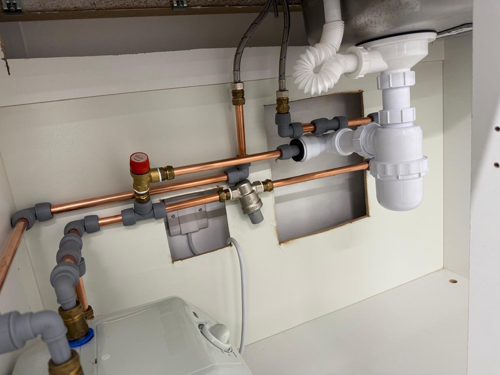 Copper pipework and valves installed beneath a commercial sink
