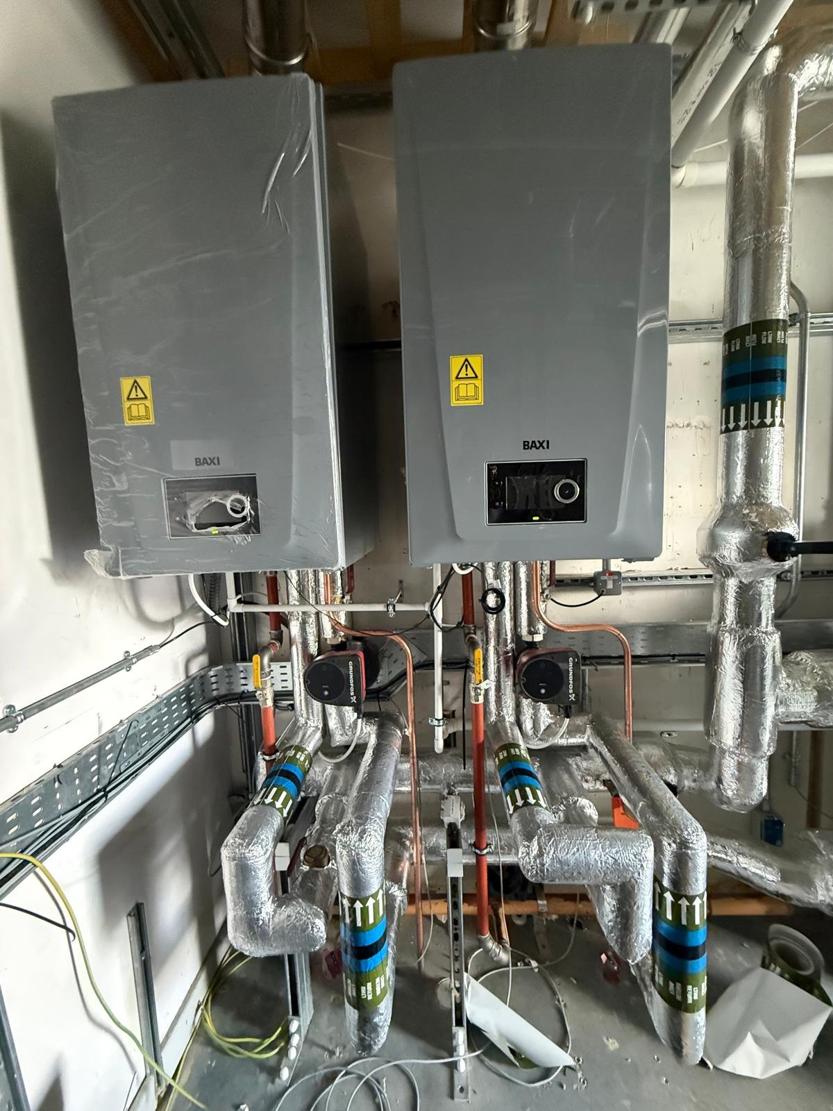 Pair of wall-mounted commercial boilers with insulated pipework