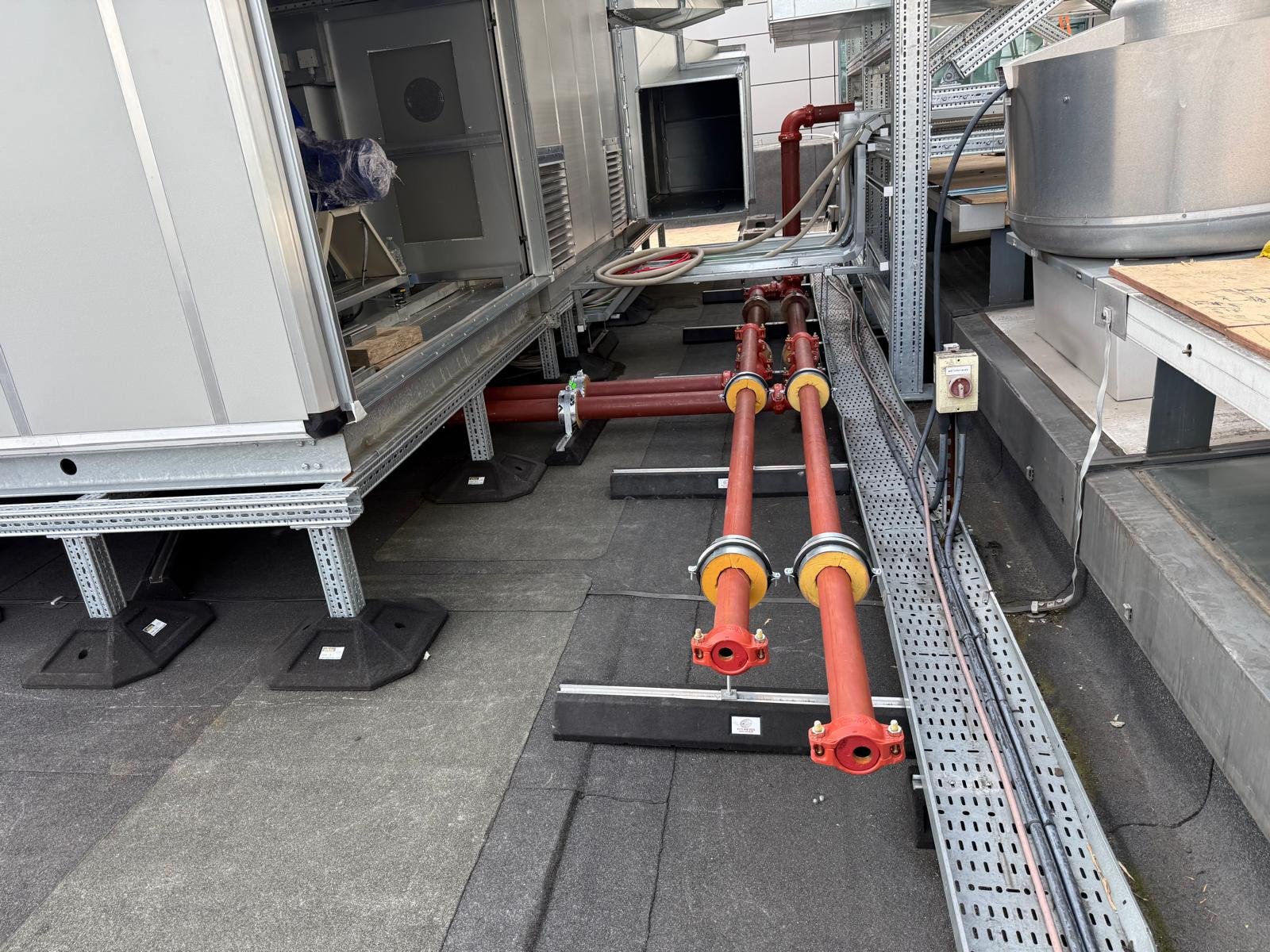 Air handling units and red pipework on a commercial rooftop